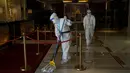 Seorang pekerja yang mengenakan pakaian pelindung diri atau hazmat membersihkan area lobi Hotel Shangri-La pada Olimpiade Musim Dingin 2022, 16 Februari 2022, di Beijing. (AP Photo/Jae C.Hong)