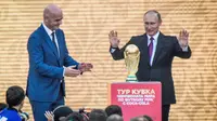 Presiden Rusia Vladimir Putin dan Presiden FIFA, Gianni Infantino saat memperlihatkan trofi Piala Dunia dalam pembukaan upacara  "FIFA World Cup Trophy Tour" di stadion Luzhniki di Moskow (9/9). (AFP Photo/Mladen Antonov) 