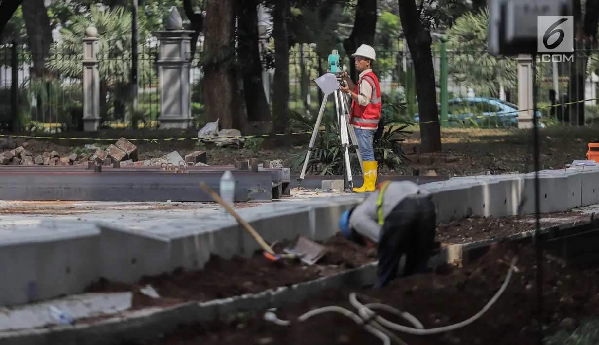 Pekerja melakukan pengukuran saat menyelesaikan proyek pembangunan mass rapid transit (MRT) fase II rute Bundaran HI-Kota di Taman Monumen Nasional (Monas), Jakarta, Selasa (2/7/2019). Seluruh stasiun MRT fase II akan berada di bawah tanah. (Liputan6.com/Faizal Fanani)