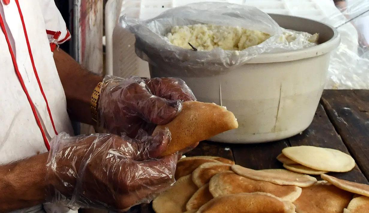 Seorang pedagang Suriah membuat "Qatayef", penganan manis tradisional yang biasa disajikan saat bulan suci Ramadan di Damaskus, Suriah, (18/5/2020). (Xinhua/Ammar Safarjalani)