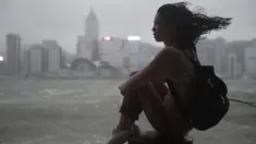 Seorang wanita melihat ke arah Victoria Harbour saat angin kencang dan hujan yang ditimbulkan oleh topan Hato di Hong Kong (23/8). Terjangan topan Hato mengakibatkan lebih dari 400 penerbangan dibatalkan. (AFP/Anthony Wallace)
