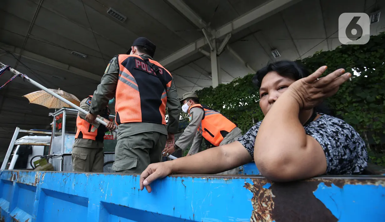 Seorang wanita duduk dalam truk saat petugas Satpol PP menertibkan PKL yang bandel berjualan di trotoar Pasar Tanah Abang, Jakarta, Senin (4/10/2021). Penertiban dilakukan untuk memberikan kenyamanan dan keamanan bagi para pengguna jalan yang melintas di trotoar tersebut. (Liputan6.com/Angga Yuniar)