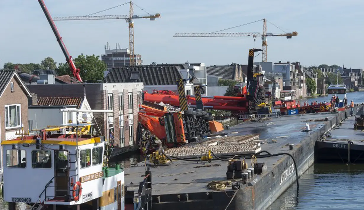 Dua mesin derek jatuh ke rumah warga di Alphen aan den Rijn, Belanda, Senin (3/8/2015) waktu setempat. Dua mesin derek yang sedang memperbaiki jembatan ambruk ke rumah yang ada di dekatnya dan melukai 20 orang. (AFP PHOTO/ANP/LEX VAN LIESHOUT)
