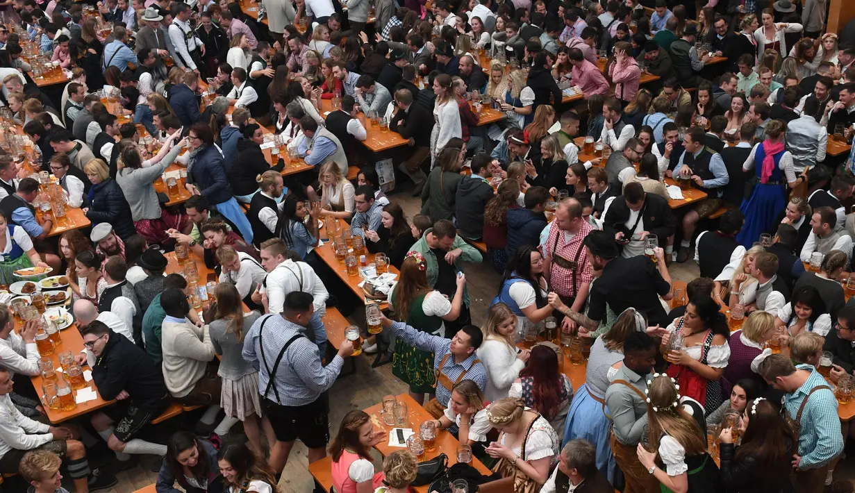 Pengunjung menikmati bir selama Festival Oktoberfest 2019 di sebuah tenda di Munich, Jerman selatan (3/10/2019). Festival bir terbesar di dunia Oktoberfest berlangsung hingga 6 Oktober 2019. (AFP Photo/Christof Stache)