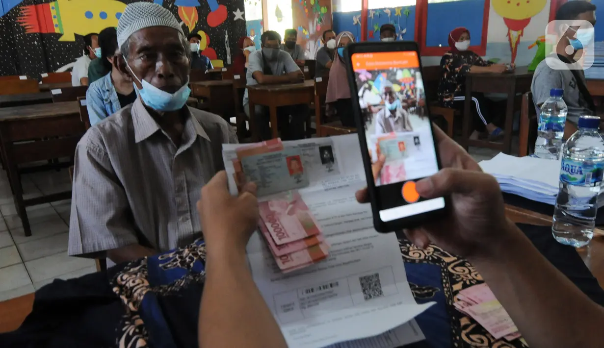 Petugas memotret warga penerima Bantuan Sosial Tunai (BST) di SDN Pondok Cabe Udik 03, Tangerang Selatan, Rabu (28/07/2021). Lebih dari dari 1800 warga mendapatkan BST yang dirapel dua bulan sekaligus dengan total Rp600ribu. (merdeka.com/Arie Basuki)