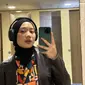 Zara melakukan mirror selfie. Dia mengenakan blouse yang dipadukan dengan jaket kulit dan jilbab hitam. Tampilannya begitu modis. (Foto: Instagram/ camilliazr)