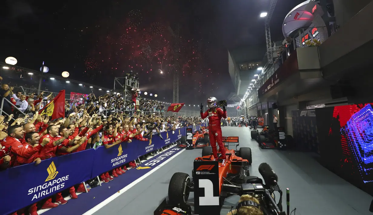 Pembalap Ferrari Sebastian Vettel berselebrasi di atas mobilnya setelah memenangkan balapan F1 GP Singapura di Sirkuit Jalan Marina Bay, Singapura (22/9/2019). Vettel kini memegang rekor kemenangan terbanyak di Singapura (2011, 2012, 2013, 2015,2019). (AP Photo/Lim Yong Teck)