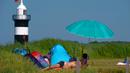 Warga berjemur saat suhu mencapai 34 derajat Celcius di dekat pantai Laut Utara di Wremen, Jerman barat (24/7/2019). Peramal cuaca memprediksi suhu tertinggi di seluruh Eropa barat yang terkena gelombang panas akan mencetak rekor suhu terbaru.  (AFP Photo/Patrik Stollarz)