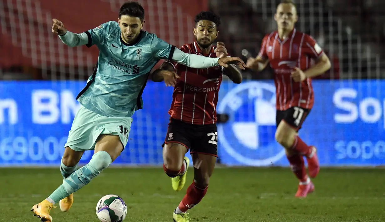 Gelandang Liverpool, Marko Grujic, berebut bola dengan gelandang Lincoln City, Liam Bridcutt , pada babak ketiga Piala Liga Inggris di Sincil Bank Stadium, Jumat (25/9/2020). Liverpool menang telak 7-2 atas Lincoln. (AFP/Peter Powell/pool)