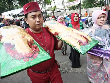 Warga membawa roti buaya saat meramaikan Festival Palang Pintu 2016 di Kemang, Jakarta, (28/5). Festival tersebut menampilkan budaya Betawi di sepanjang Jalan Kemang Raya dengan dua panggung utama dan sekitar 270 booth. (Liputan6.com/Immanuel Antonius)