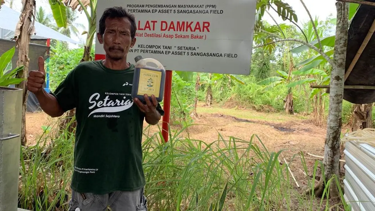 Sutrimo, Ketua Kelompok Setaria di Sangasanga, Kutai Kartanegara, Kalimantan Timur, memamerkan produk pupuk cair yang berasal dari inovasi DAMKAR, Alat Destilasi Asap Sekam Bakar.