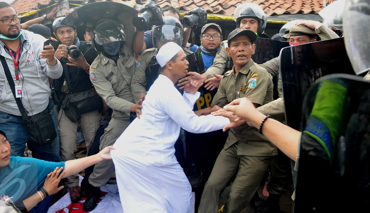Seorang warga yang mencoba menghalangi penggusuran Pasar Ikan, Penjaringan, Jakarta, ditarik paksa oleh Satpol PP, Senin (11/4). Penertiban sempat diwarnai bentrokan antara petugas dan warga yang menolak penggusuran. (Liputan6.com/Gempur M Surya)