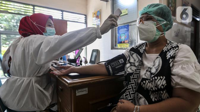 Petugas medis memeriksa suhu tubuh tenaga kesehatan sebelum disuntik vaksin COVID-19 Sinovac di Puskesmas Palmerah, Jakarta, Kamis (28/1/2021). Pemberian vaksin COVID-19 tahap kedua dilaksanakan terhadap tenaga kesehatan mulai hari ini. (Liputan6.com/Johan Tallo)