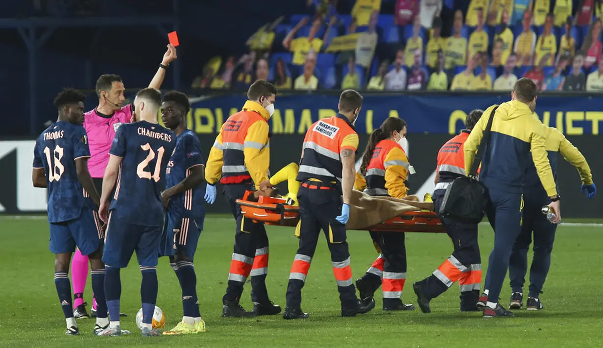 Pemain Villareal Etienne Capoue mendapat kartu merah dari wasit saat dia dibawa dari lapangan karena cedera pada pertandingan leg pertama semifinal Liga Europa melawan Arsenal di Stadion Estadio de la Ceramica, Villarreal, Spanyol, Kamis (29/4/2021). Villareal menang 2-1. (AP Photo/Alberto Saiz)