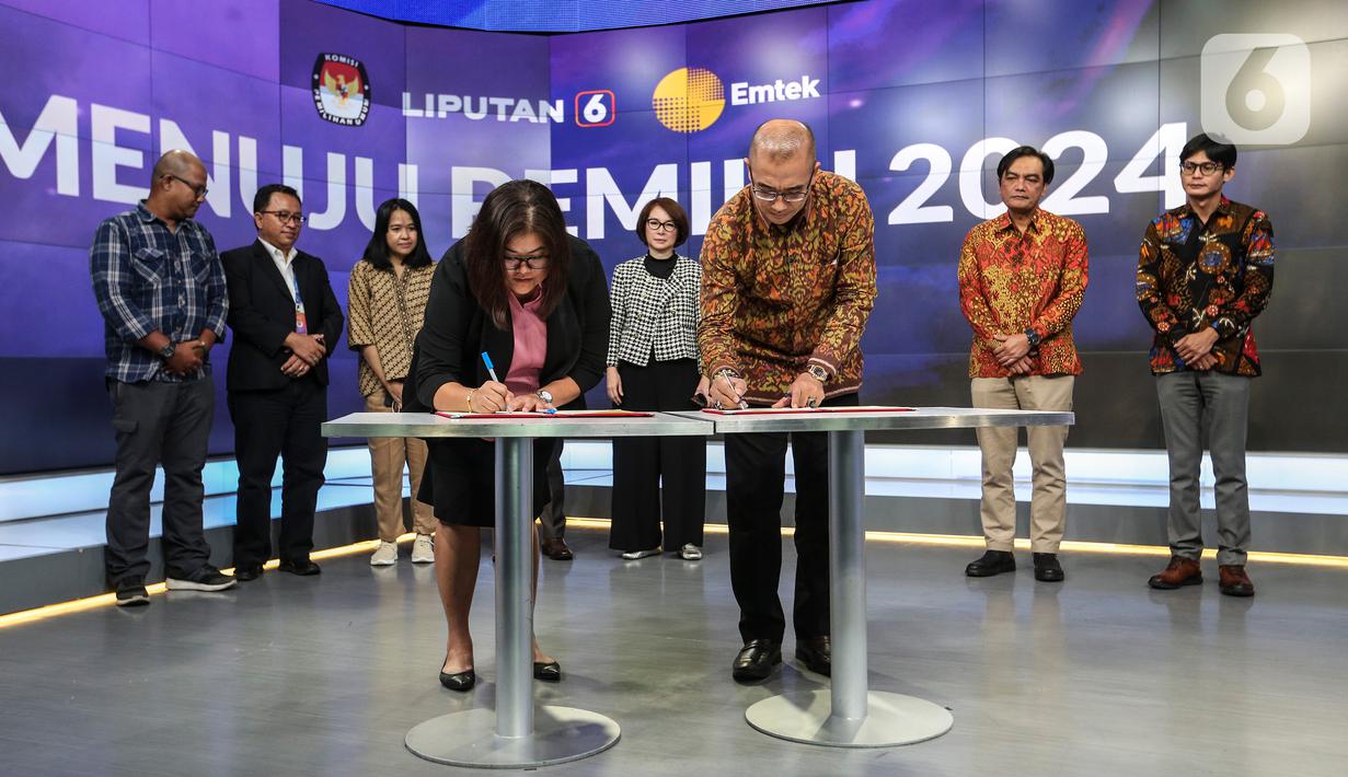 Ketua Komisi Pemilihan Umum (KPU) Hasyim Asy'ari (tengah kanan) bersama CFO KLY Octaviany Sarimawan (tengah kiri) menandatangani dokumen kerja sana saat acara penandatanganan MoU antara Emtek dengan KPU di SCTV Tower, Jakarta, Selasa (30/8/2022). Kerja sama KPU dengan Emtek ini terkait sosialisasi Pemilihan Umum yang akan diselenggarakan 2024 mendatang. (Liputan6.com/Johan Tallo)