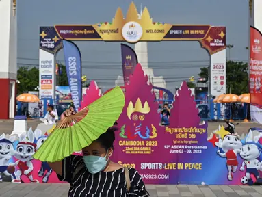 Seorang wanita memegang kipas angin untuk melindungi dirinya dari sinar matahari di luar Stadion Nasional Morodok Techo, Phnom Penh, Jumat 5 Mei 2023. (NHAC NGUYEN/AFP)