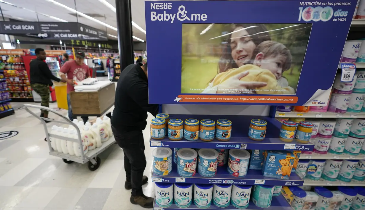 <p>Seorang pekerja toko kelontong menata rak berisi merek susu formula bayi di belakang iklan digital di Tijuana, Meksiko, Selasa (24/5/2022). Saat susu formula di sejumlah supermarket Amerika Serikat hampir kosong, justru rak-rak susu di supermarket Meksiko terlihat penuh dengan berbagai pilihan. (AP Photo/Gregory Bull)</p>