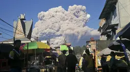 Orang-orang menyaksikan Gunung Sinabung memuntahkan material vulkanik saat meletus di Karo, Sumatera Utara, Selasa (2/3/2021).  Erupsi Gunung Sinabung juga mengendapkan abu di desa-desa terdekat. (AP Photo/Sugeng Nuryono)