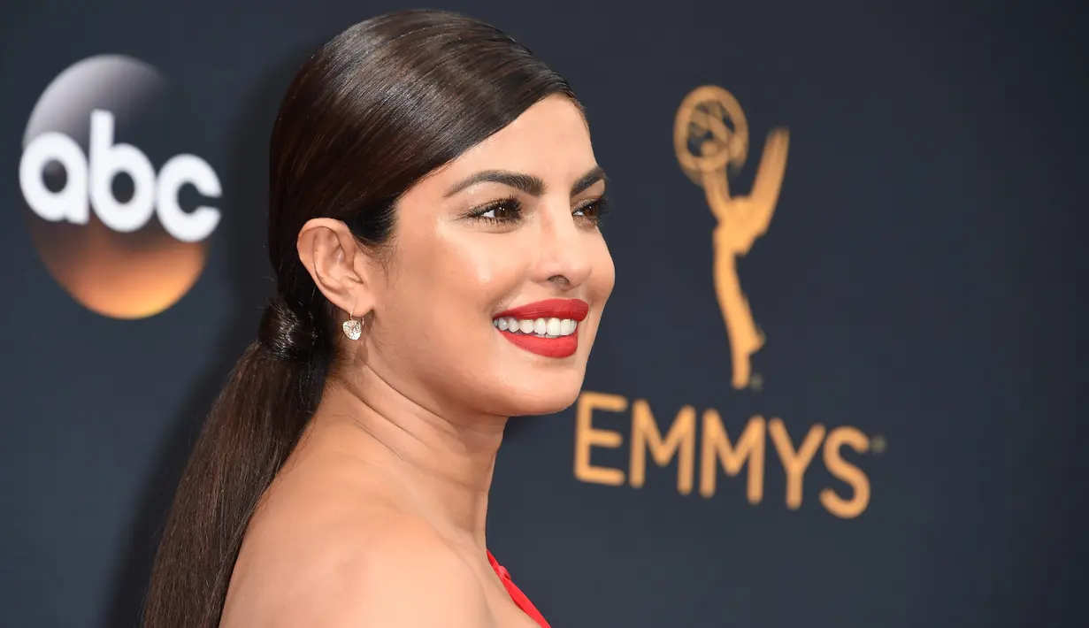 Aktris Bollywood Priyanka Chopra membiarkan rambutnya terikat rapi ketika menghadiri ajang Emmy Awards 2016 di Microsoft Theater, Los Angeles, Minggu (18/9). Priyanka  menyempurnakan penampilannya dengan pulasan lipstik merah. (AFP PHOTO/Robyn Beck)