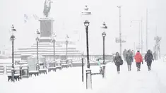 Orang-orang berjalan saat salju turun di Skeppsbron di Stockholm, Swedia (28/1/2021). Badan cuaca nasional Swedia, SMHI, telah mengeluarkan peringatan untuk salju lebat di Stockholm dan Uppsala. (Henrik Montgomery/TT via AP)