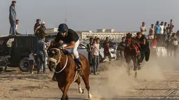 Sejumlah joki memacu kudanya saat bersaing dalam balap kuda di Rafah, Jalur Gaza, Palestina, Selasa (10/9/2019). Balapan kuda tradisional Palestina tersebut digelar di bekas lokasi bandara Jalur Gaza yang telah hancur. (AFP Photo/Said Khatib)