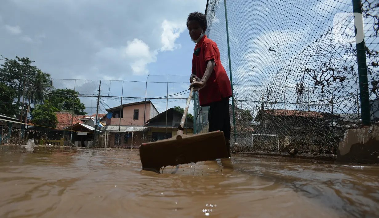 Warga membersihkan lumpur sisa banjir di Kelurahan Rawa Jati, Jakarta, Selasa (9/2/2021). Endapan lumpur yang mengendap akibat luapan Kali Ciliwung. (merdeka.com/Imam Buhori)