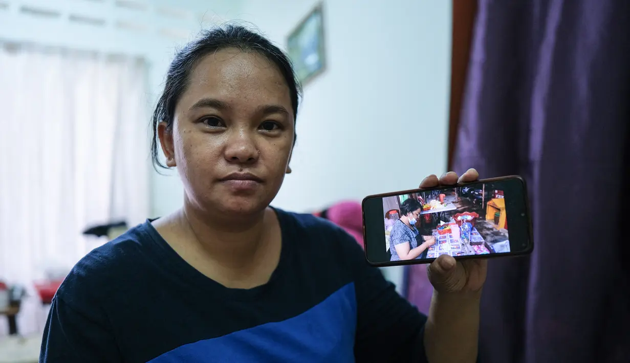 Ibu tunggal Tilda Kalaivani menunjukkan fotonya saat bekerja sebagai penjual bunga sebelum lockdown di apartemen sewaannya di Kuala Lumpur pada 6 Juli 2021. Akibat lockdown nasional, banyak keluarga berpenghasilan rendah yang terdampak pandemi semakin kesulitan menjalani hidup. (Mohd RASFAN/AFP)