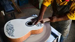 Pengrajin Salvador Meza membuat replika gitar dari film "Coco" di rumah produksinya di Paracho, Meksiko (8/1). Karena banyaknya permintaan, pengrajin ini tidak dapat memenuhi semua pesanan. (AFP Photo/ Ronaldo Schemidt)