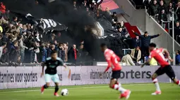 Asap hitam menyelimuti tribun penonton saat pertandingan sepak bola PSV Eindhoven vs Ajax di Stadion Philips, Belanda (23/4). Akibat asap itu beberapa penonton mengalami gangguan pernapasan dan mata. (Olaf KRAAK / ANP / AFP)