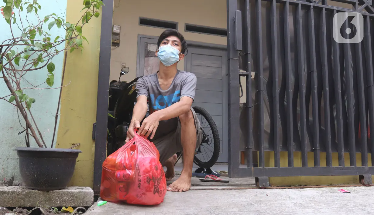 Warga menerima bantuan bahan pokok di rumahnya di RT03/RW03, Kelurahan Cilangkap, Jakarta, Jumat (21/5/2021). Bantuan sebagai bentuk kepedulian terhadap warga yang melakukan isolasi mandiri karena terkonfirmasi Covid-19. (Liputan6.com/Herman Zakharia)