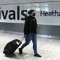 Potret yang diambil pada 10 Juli 2020 ini, menampilkan penumpang mengenakan masker akibat pandemi COVID-19, baru tiba di Bandara Heathrow, London barat. (DANIEL LEAL-OLIVAS / AFP)