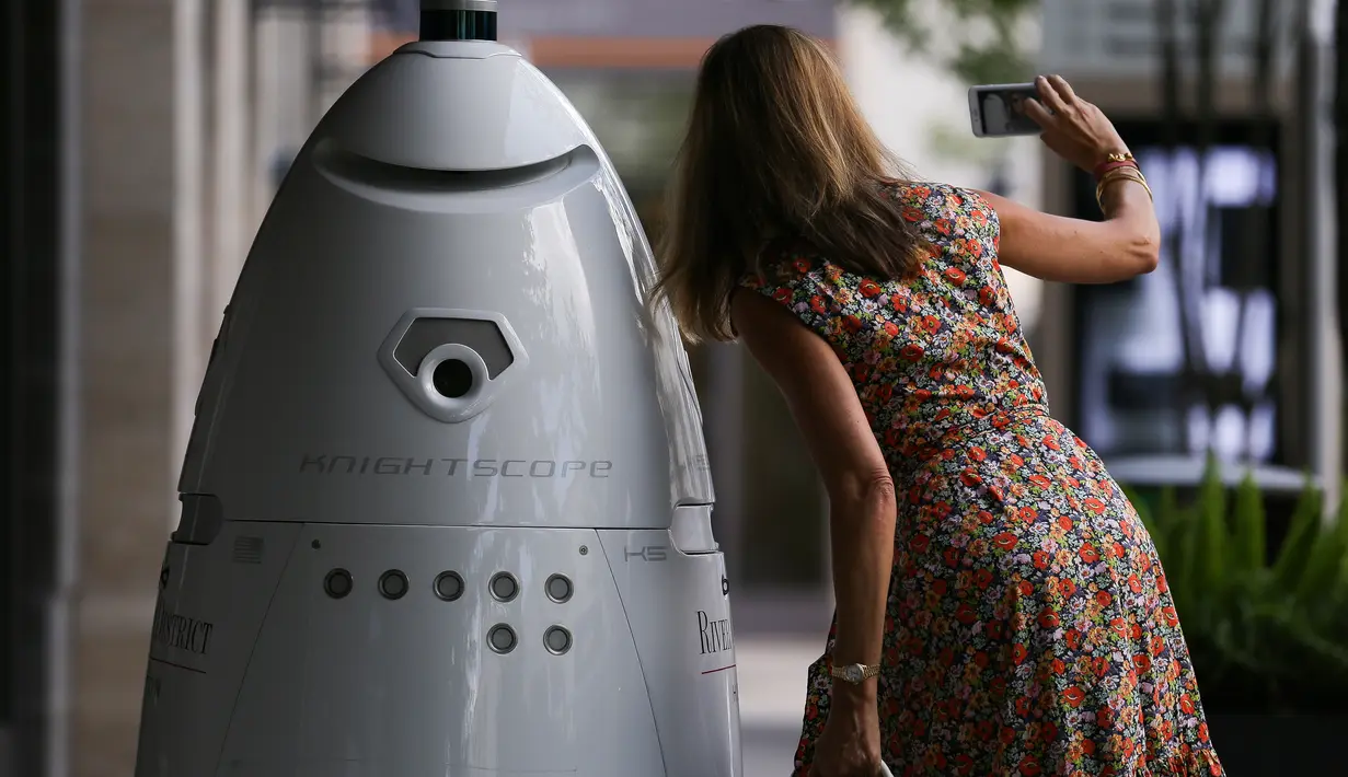Seorang wanita berswafoto bersama robot keamanan baru yang bernama ROD2 di River Oaks District, Houston (18/8). Robot baru ini menjadi tambahan untuk tim pengaman dan patroli rutin di River Oaks District. (Michael Ciaglo / Houston Chronicle via AP)
