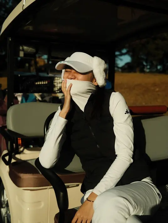 Ia memadukan baju golf khusus untuk musim dingin dengan warna serba putih. [@azizahsalsha_]