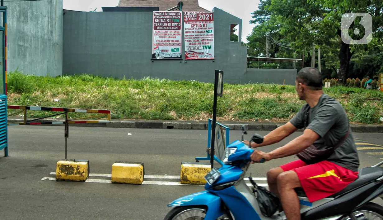 Warga melihat spanduk meminta pelantikan RT di Meruya di Perumahan Taman Villa Meruya (TMV) Meruya Selatan, Kembangan, Jakarta Barat, Sabtu (26/2/2022). (Liputan6.com/Faizal Fanani)