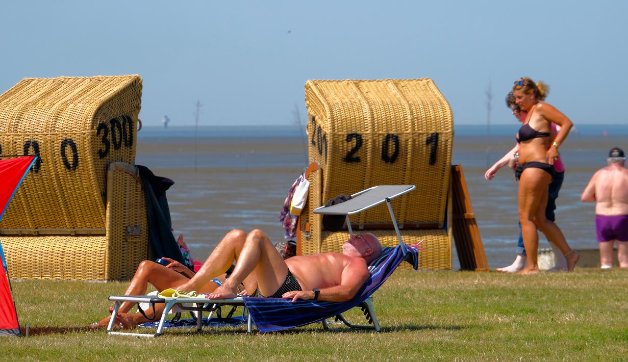 Seorang pria berjemur saat suhu mencapai 34 derajat Celcius di dekat pantai Laut Utara di Wremen, Jerman barat (24/7/2019). Peramal cuaca memprediksi suhu tertinggi di seluruh Eropa barat yang terkena gelombang panas akan mencetak rekor suhu terbaru.  (AFP Photo/Patrik Stollarz)