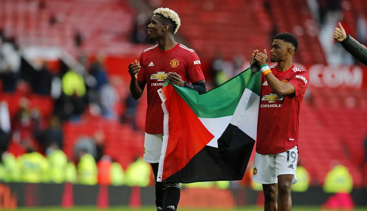 Gelandang MU, Paul Pogba dan Amad Diallo mengibarkan bendera Palestina usai ditahan imbang Fulham pada pekan ke-37 Liga Inggris di Stadion Old Trafford, Rabu (19/5/2021) dinihari WIB. Laga yang digelar di Stadion Old Trafford itu dihadiri sekitar 10 ribu penonton. (PHIL NOBLE/POOL/AFP)