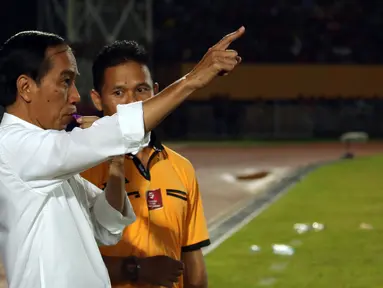 Presiden RI, Joko Widodo (kiri) meniup peluit tanda dimulainya babak kedua laga Persipura vs Persija di Torabika Soccer Championship presented by IM3 Ooredoo di Stadion Mandala Jayapura,Papua, Jumat (29/4/2016). (Liputan6.com/Helmi Fithriansyah)