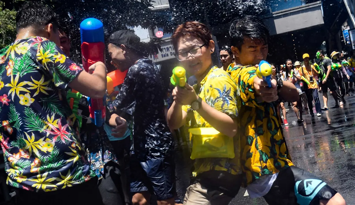 Orang-orang bersuka cita saling menyemprotkan air selama Festival Songkran di Silom Road, Bangkok, Jumat (13/4). Songkran dikenal dengan nama festival air karena warga Thailand percaya air akan menghapus nasib buruk. (LILLIAN SUWANRUMPHA/AFP)