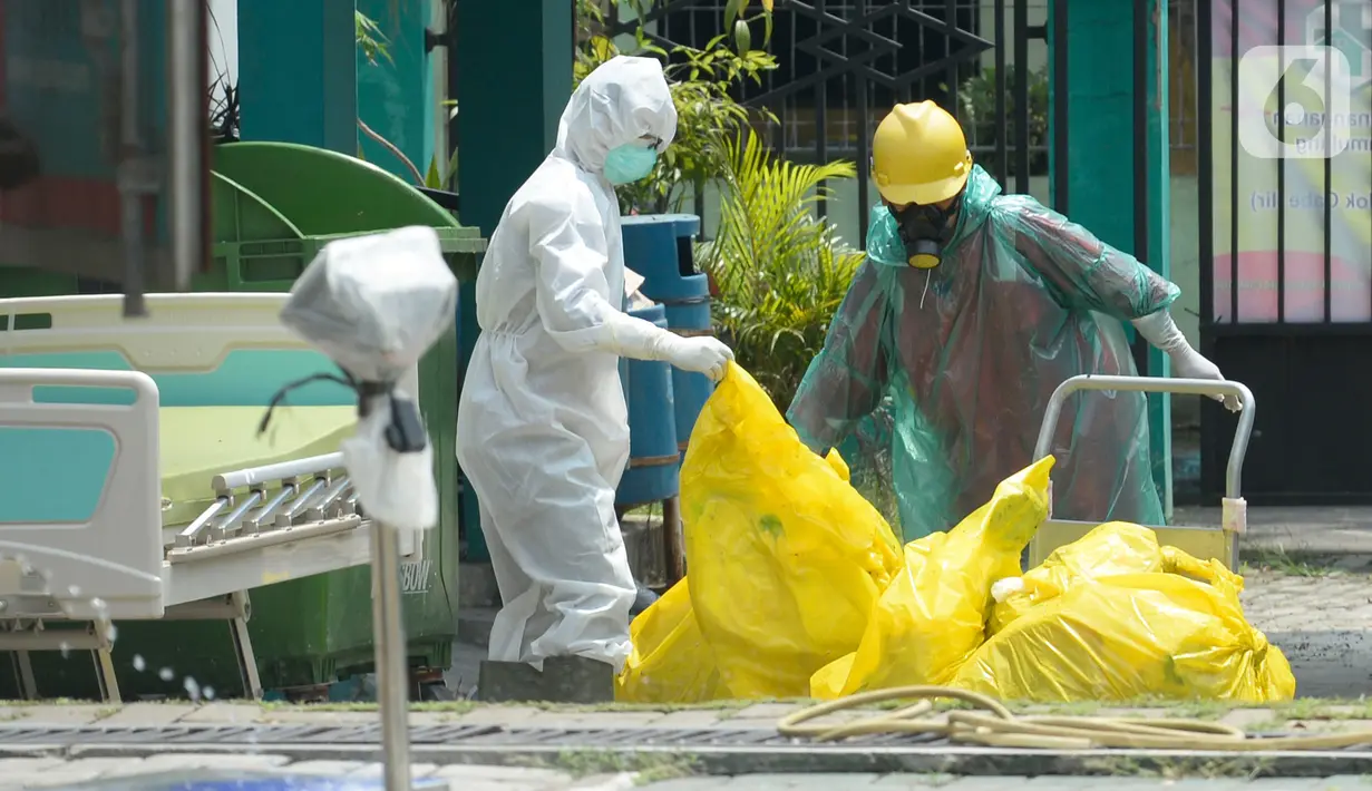 Petugas kesehatan memakai baju APD sedang membersihkan sampah bekas medis di Puskesmas Pamulang, Kecamatan Pamulang, Tangerang Selatan, Banten, Senin (13/04/2020). Sampah bekas medis tes Covid-19 tersebut akan dimusnahkan guna untuk mensteril kawasan puskesmas. (merdeka.com/Dwi Narwoko)