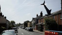 Patung dengan nama Headington Shark tampak menerobos atap rumah di wilayah pinggiran Oxford, Inggris pada 30 April 2019. Bagian kepalanya tidak terlihat karena dibuat seakan masuk ke dalam atap, sedangkan badan hingga ekornya menjulang ke langit dengan posisi terbalik.  (AP Photo/Matt Dunham)