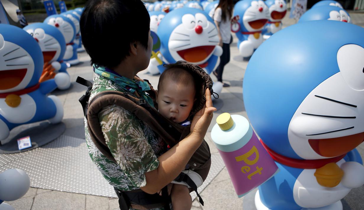 Seorang wanita saat menggendong anaknya untuk melihat patung karakter kartun terkenal Doraemon di Seoul, Korea Selatan,Senin (31/8/2015). Pameran ini menghadirkan seratus patung Doraemon  dengan berbagai pose yang berbeda. (REUTERS/Kim Hong – Ji)   