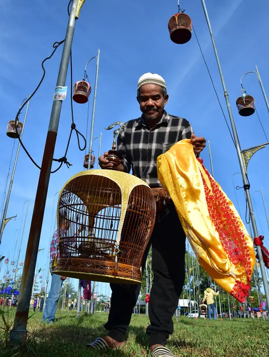Seorang pria mempersiapkan sangkar yang didalamnya terdapat seekor burung untuk ikut serta dalam kompetisi nyanyian di Narathiwat, Thailand, Rabu (21/9/2022). Sekitar 1.500 burung dari Thailand, Malaysia dan Singapura diikutsertakan dalam kontes tahunan ini. (Madaree TOHLALA / AFP)