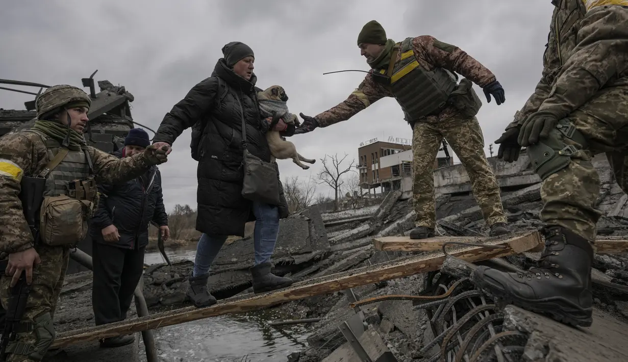 Prajurit Ukraina membantu seorang perempuan yang membawa seekor anjing kecil melintasi Sungai Irpin di jalur improvisasi sambil membantu orang-orang yang melarikan diri dari kota Irpin, Ukraina, 5 Maret 2022. (AP Photo/Vadim Ghirda)