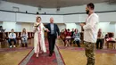 Anna Sokurenko didampingi oleh ayahnya menuju tentara Ukraina Vitalii Khroniuk saat upacara pernikahan mereka di Kiev, Ukraina, 7 Februari 2023. Saat Khroniuk terbaring telungkup di tanah berlindung dari tembakan artileri Rusia, prajurit Ukraina hanya memiliki satu penyesalan : Dia belum pernah punya anak. (AP Photo/Evgeniy Maloletka)