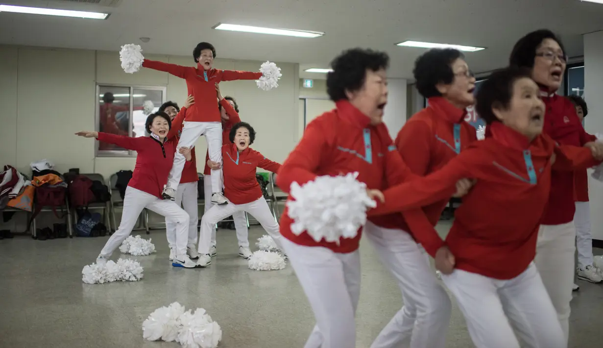 Suasana latihan anggota cheerleaders Cheer Mommy di ruang latihan di Samcheok, Korsel (3/3). Mereka mengenakan baju seragam merah lengkap dengan pom-pomnya melakukan gerakan layakanya pemandu sorak umumnya. (AFP/Ed Jones)