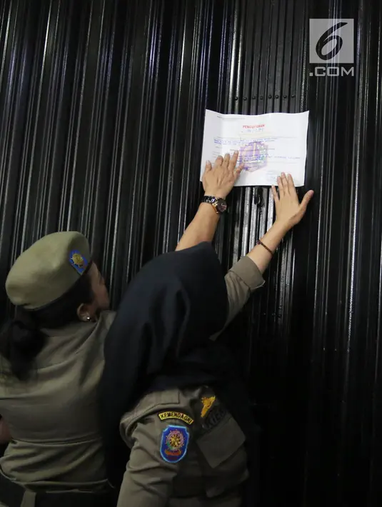 Petugas Satpol PP wanita menempelkan stiker penutupan di pintu masuk Diskotek Exotic di Mangga Besar, Jakarta, Kamis (19/4). Penyegelan oleh petugas ini hanya disaksikan warga tanpa perlawanan yang berarti dari pihak diskotek. (Liputan6.com/Arya Manggala)