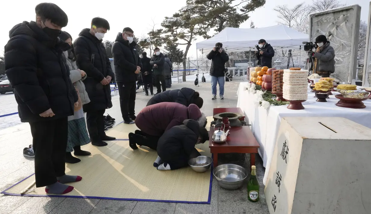 Pengungsi Korea Utara dan anggota keluarganya membungkuk memberikan penghormatan kepada leluhur mereka untuk merayakan tahun Baru Imlek saat mengunjungi Paviliun Imjingak dekat perbatasan dengan Korea Utara, di Paju, Korea Selatan, Selasa (1/2/2022). (AP Photo/Ahn Young-joon)