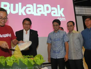 CEO dan founder Bukalapak Achmad Zaky (kiri) memotong tumpeng disaksikan Menkominfo Rudiantara (kedua kiri) saat perayaan ulang tahun yang ke-6 serta peresmian kantor baru mereka di kawasan Kemang, Jakarta, Selasa (12/1). (Liputan6.com/Faisal R Syam)