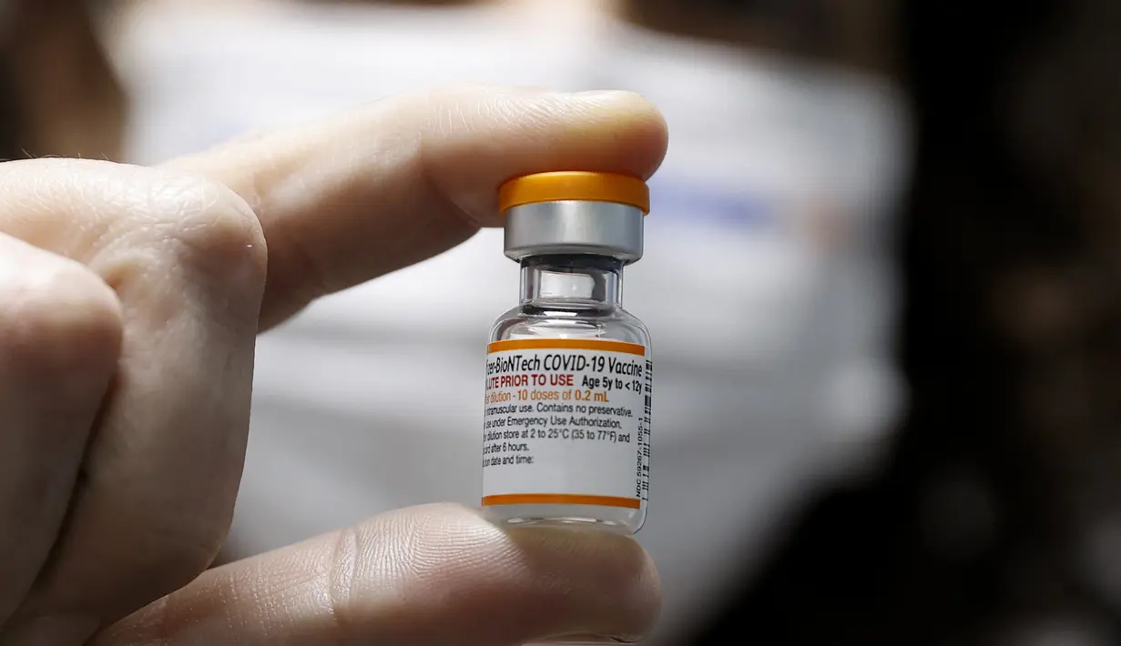 Seorang pekerja kesehatan Israel menunjukkan botol vaksin Covid-19 Pfizer/BioNTech Covid-19 untuk anak-anak di Meuhedet Healthcare Services Organization di Tel Aviv, saat Israel memulai kampanye vaksinasi virus corona untuk anak berusia 5 hingga 11 tahun, Senin (22/11/2021). (JACK GUEZ / AFP)