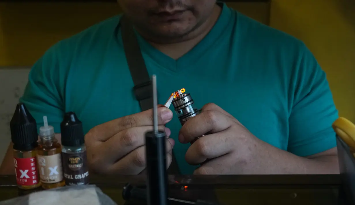 Seorang pelanggan mempersiapkan rokok elektrik di sebuah toko vape di Manila (20/11/2019). Presiden Filipina Rodrigo Duterte mengumumkan akan melarang penggunaan e-rokok dan memerintahkan polisi untuk menangkap orang-orang yang merokok e-rokok di depan umum. (AFP Photo/Dante Diosina Jr)